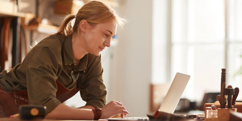 young woman in carpentry shop working on laptop